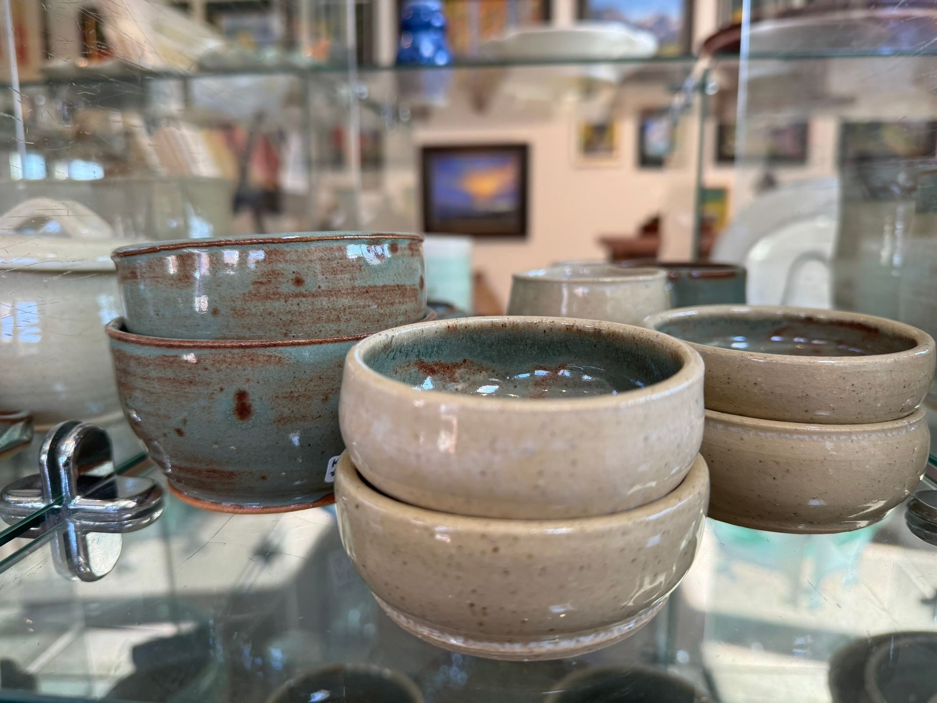 A group of small bowls stacked on top of each other on a glass shelf.