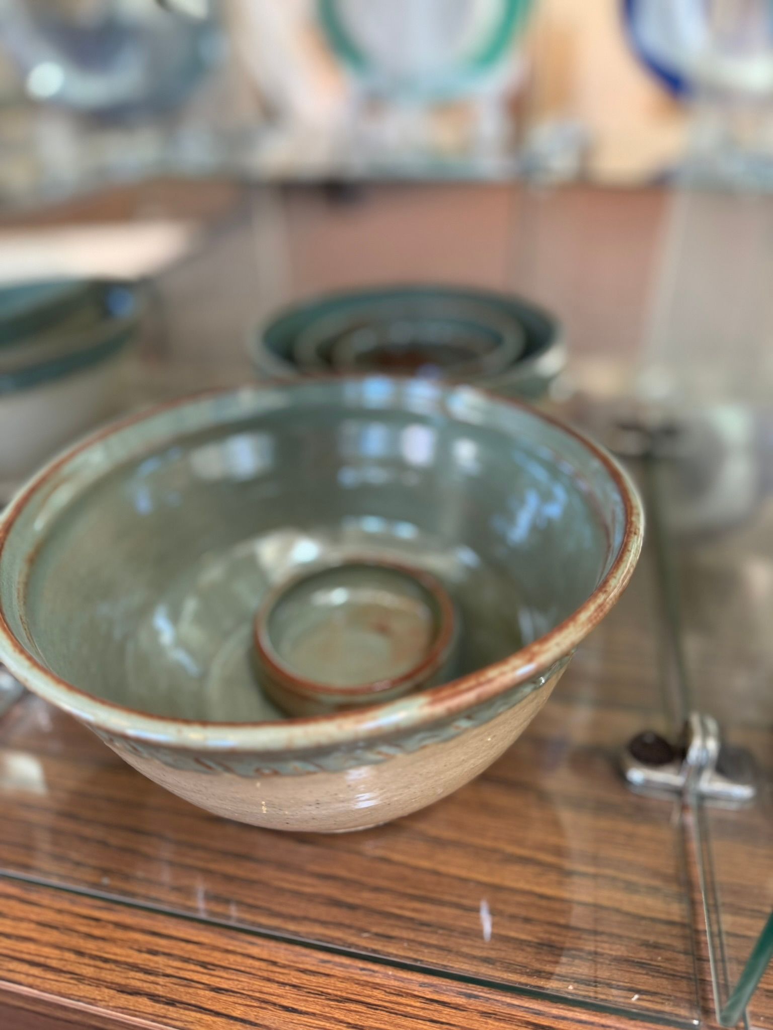 A green bowl is sitting on top of a glass table.