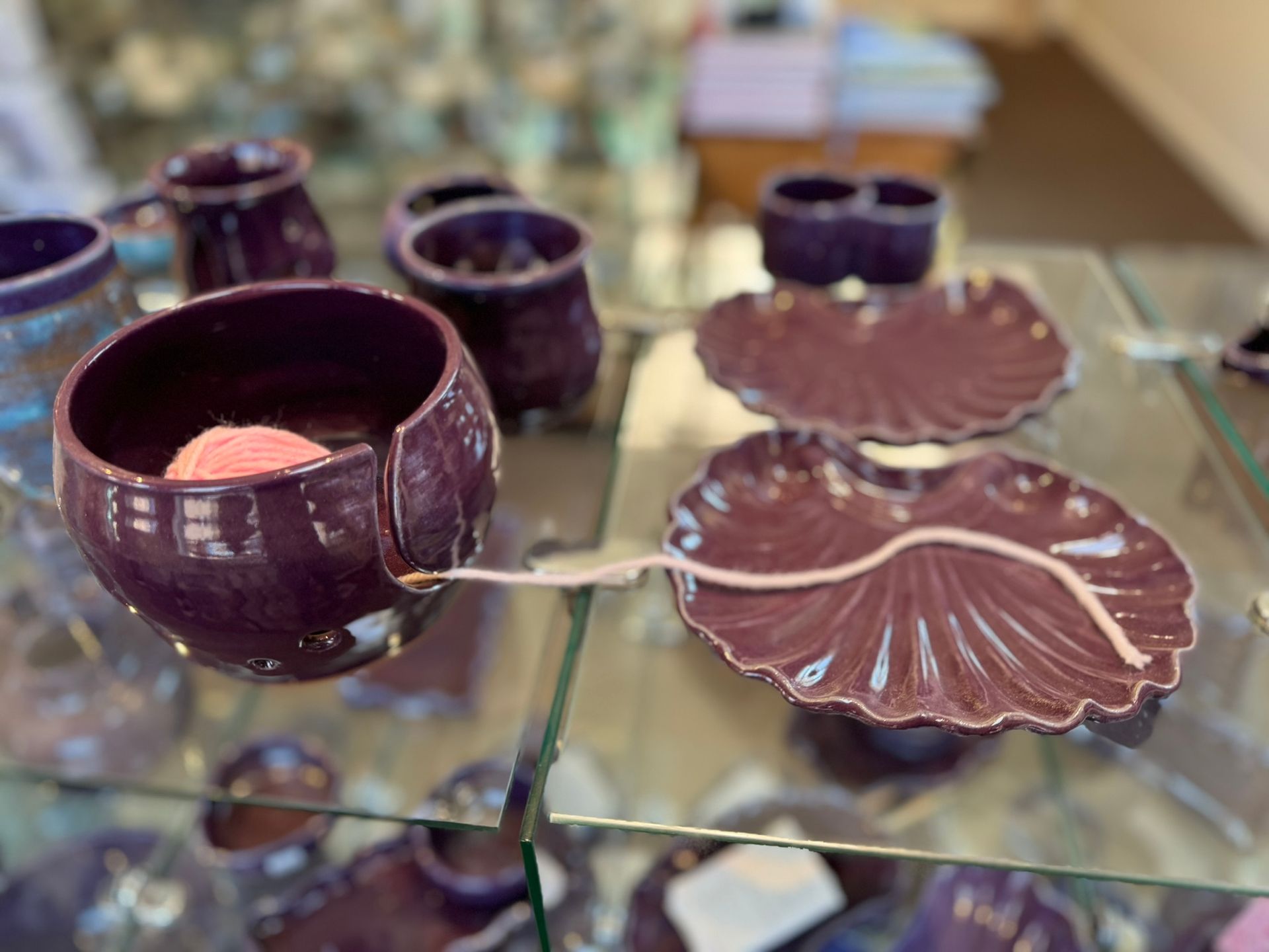 A glass display case filled with purple bowls and plates.