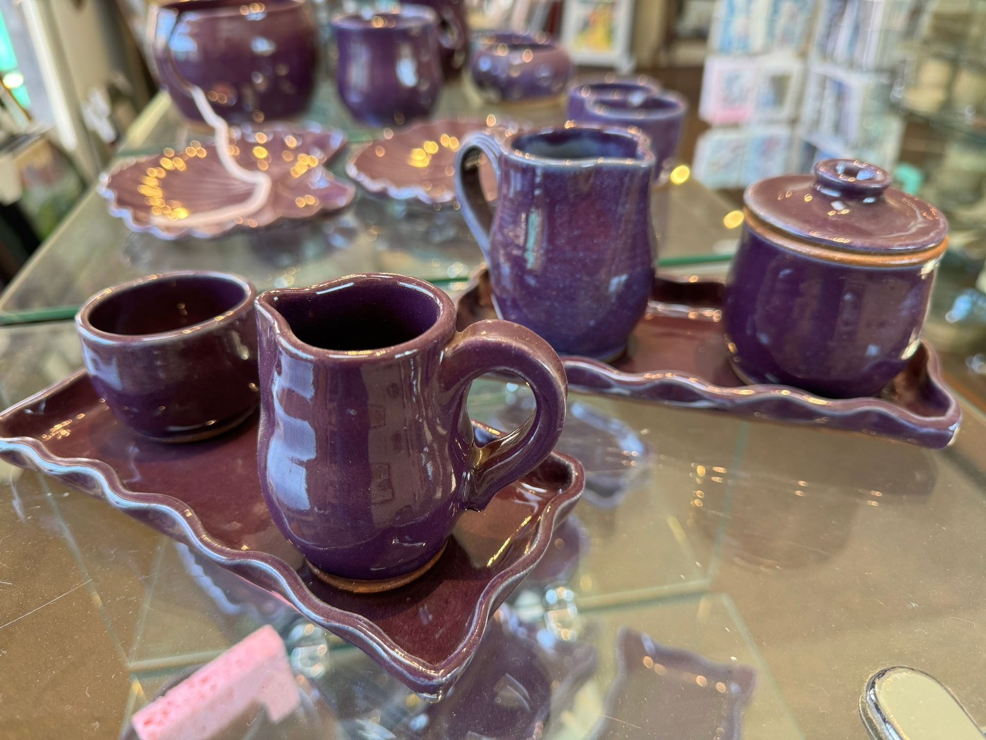 A purple pottery set is sitting on a glass table.
