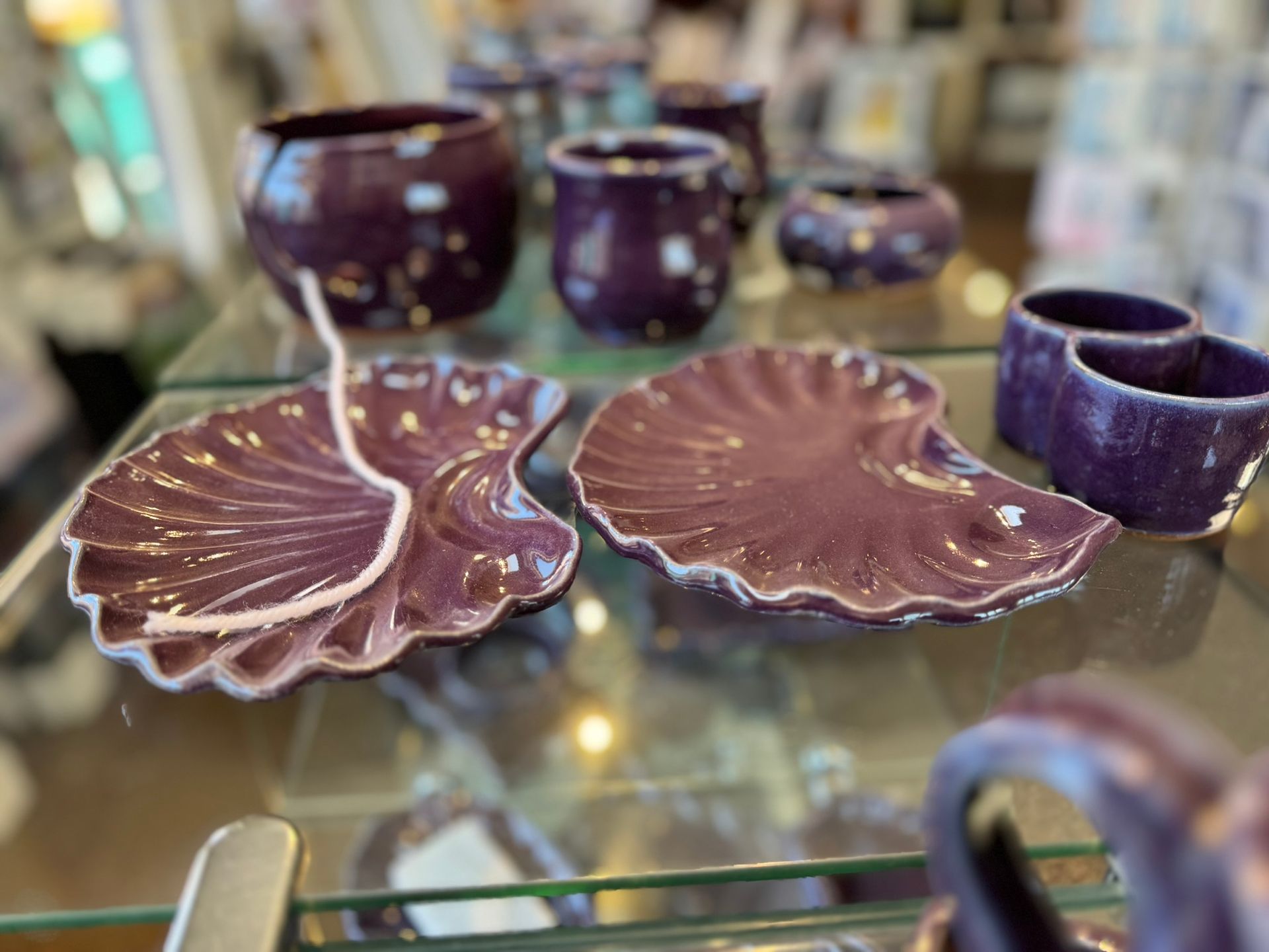 A glass shelf with purple plates and cups on it.