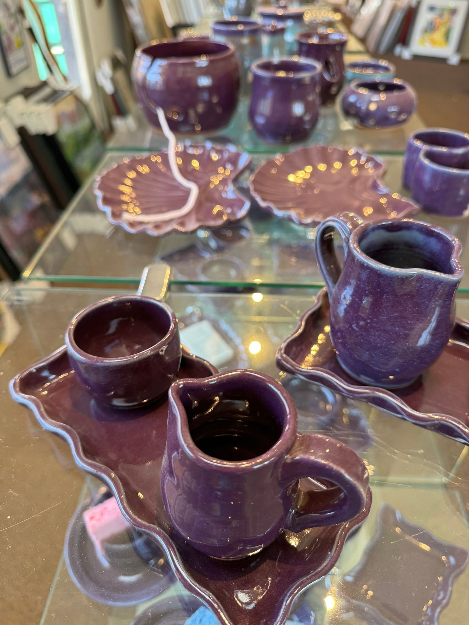 A glass table topped with purple cups and saucers.