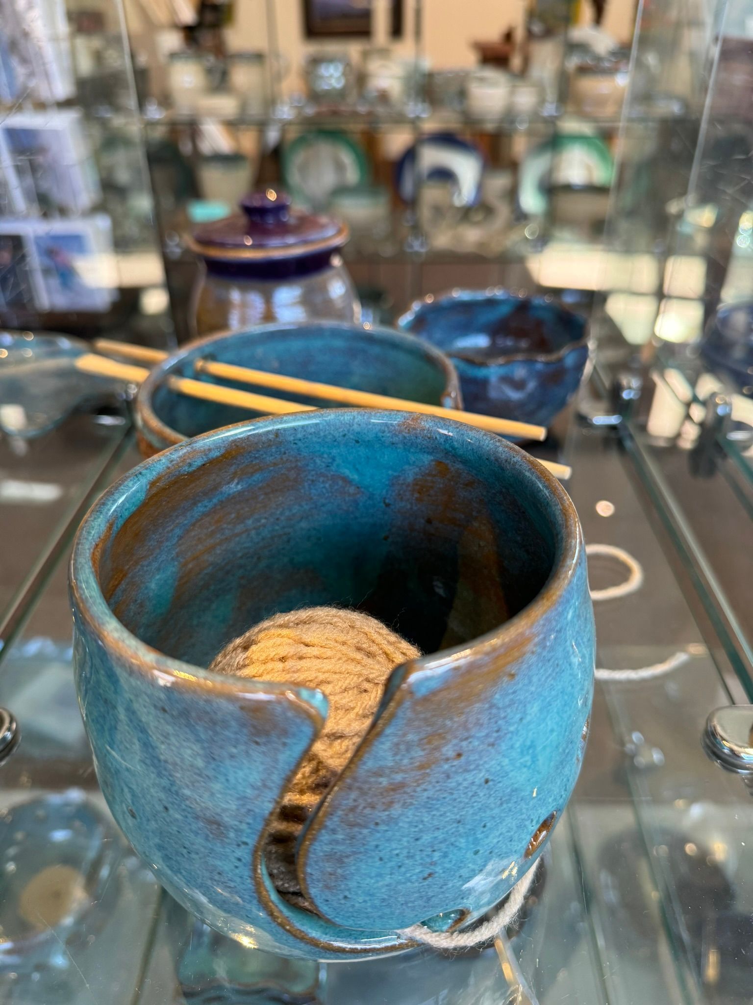A blue bowl with chopsticks in it is sitting on a glass table.