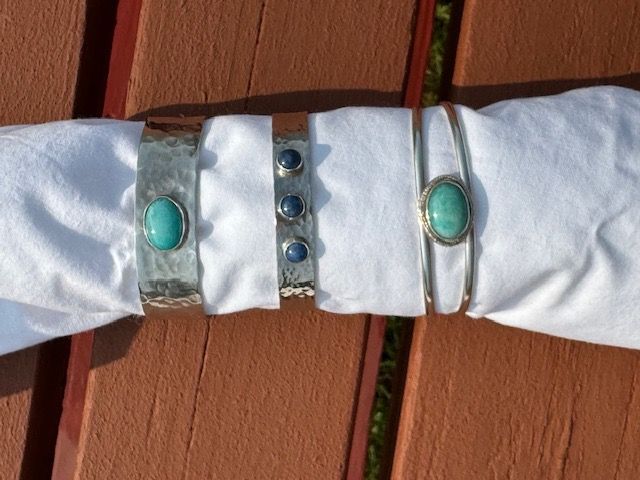 Three bracelets are wrapped in a napkin on a wooden table.