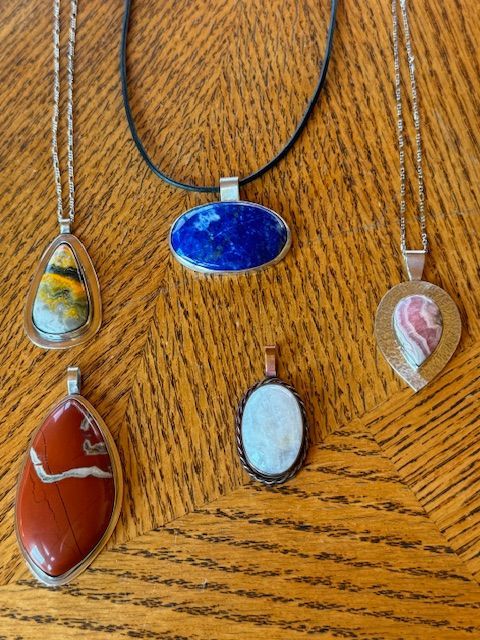 A group of necklaces are sitting on a wooden table.