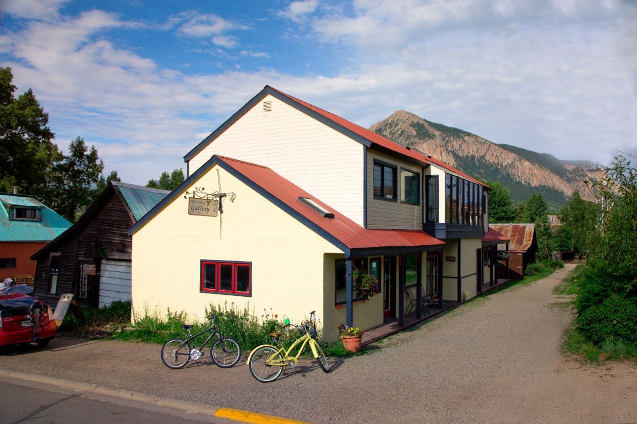 Two bicycles are parked in front of a house with a mountain in the background