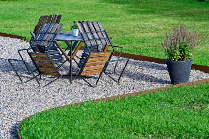 A table and chairs are sitting on a gravel path in the grass.