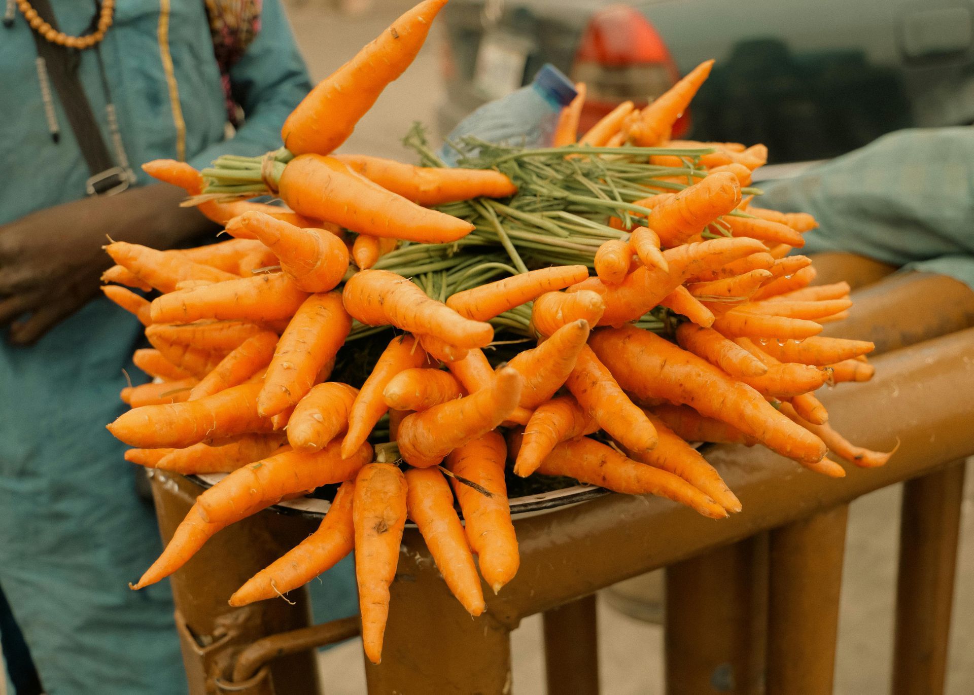 A pile of fresh orange carrots on a wooden table at a market stall