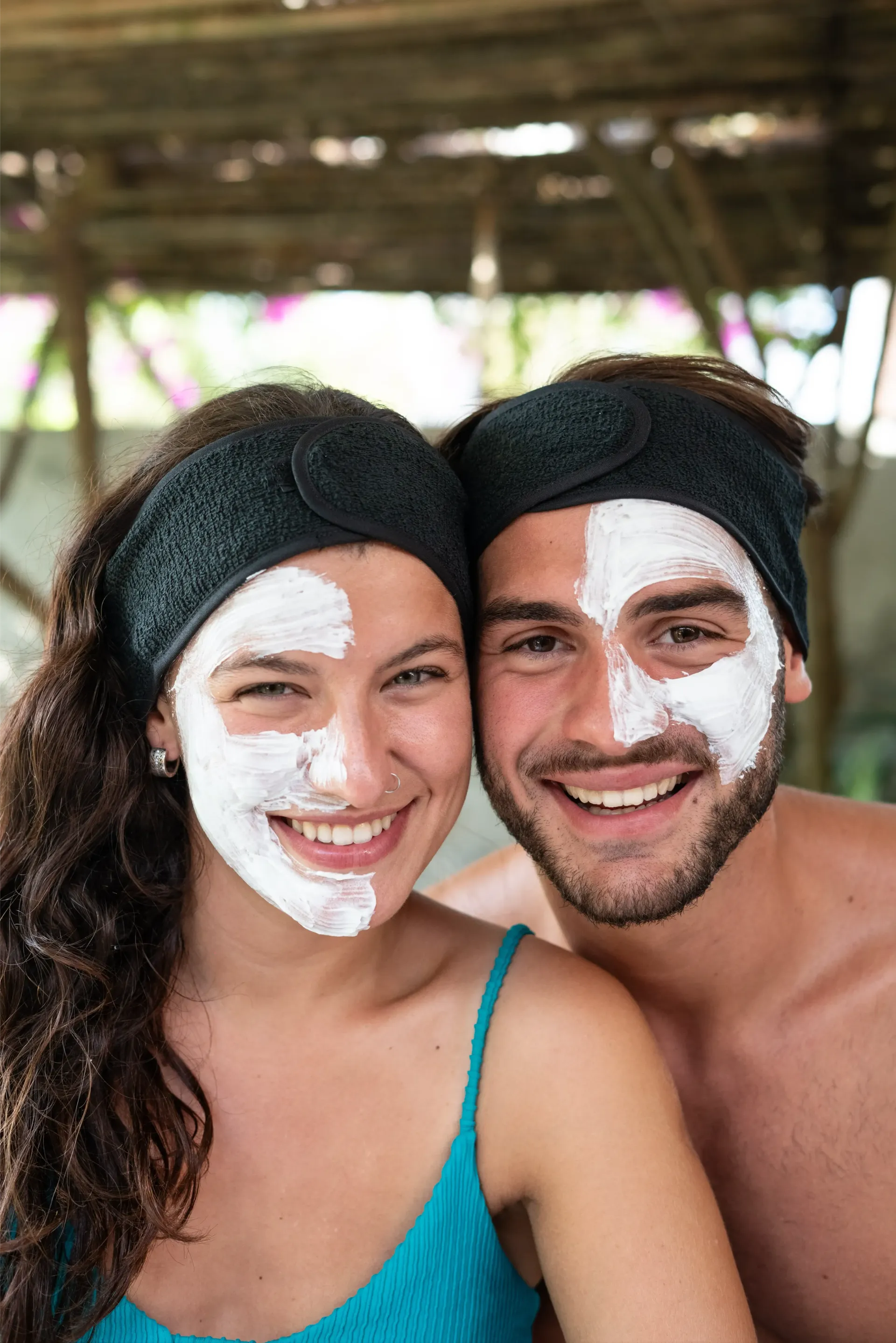 Pareja sonriente con máscaras faciales blancas; usando diademas; al aire libre.