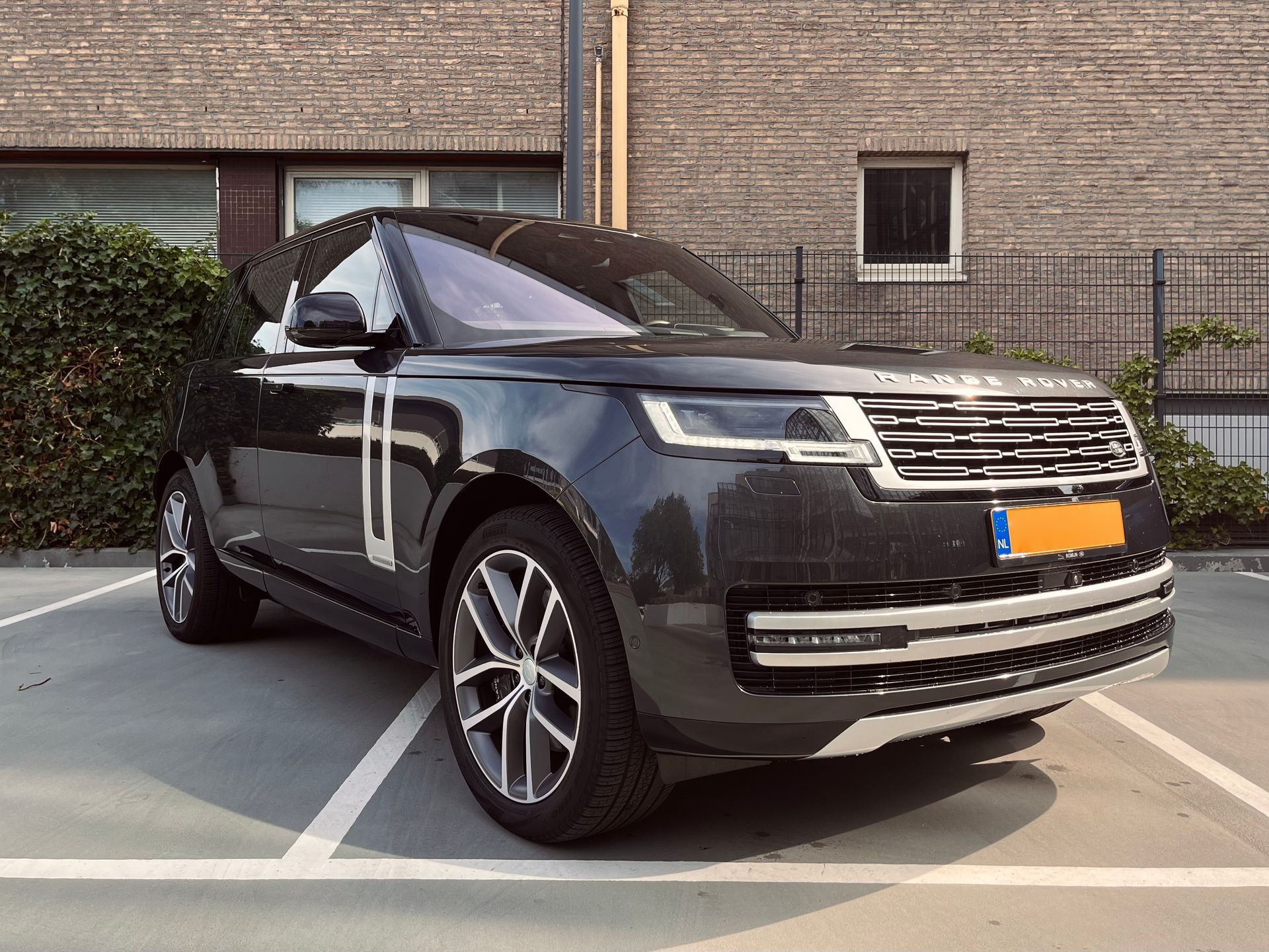 Een donkergrijze Range Rover staat geparkeerd op een parkeerterrein