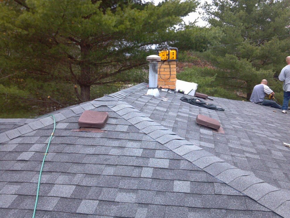 Two men are working on the roof of a house.