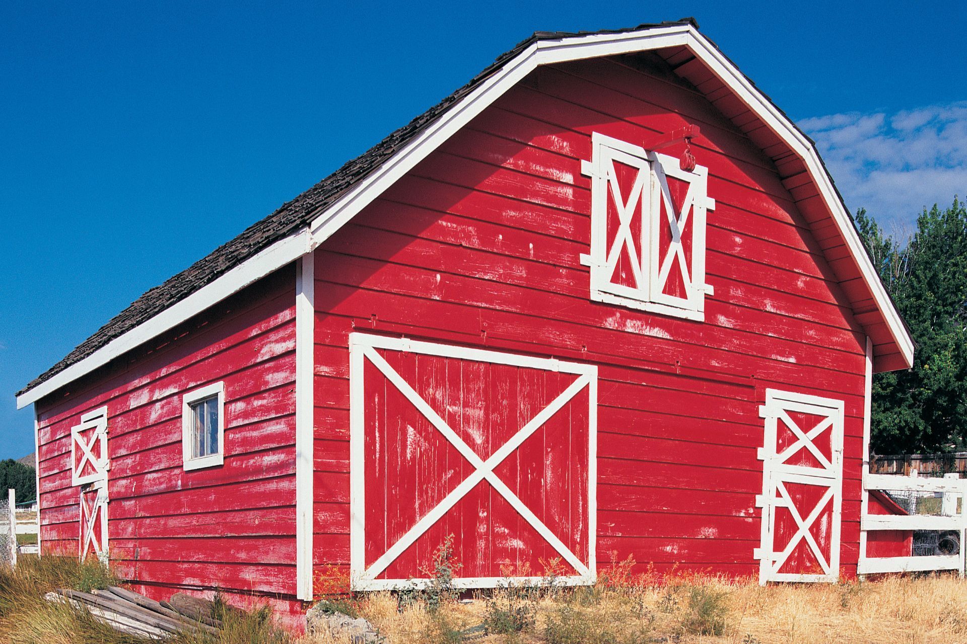 A red barn with white trim and a blue sky in the background