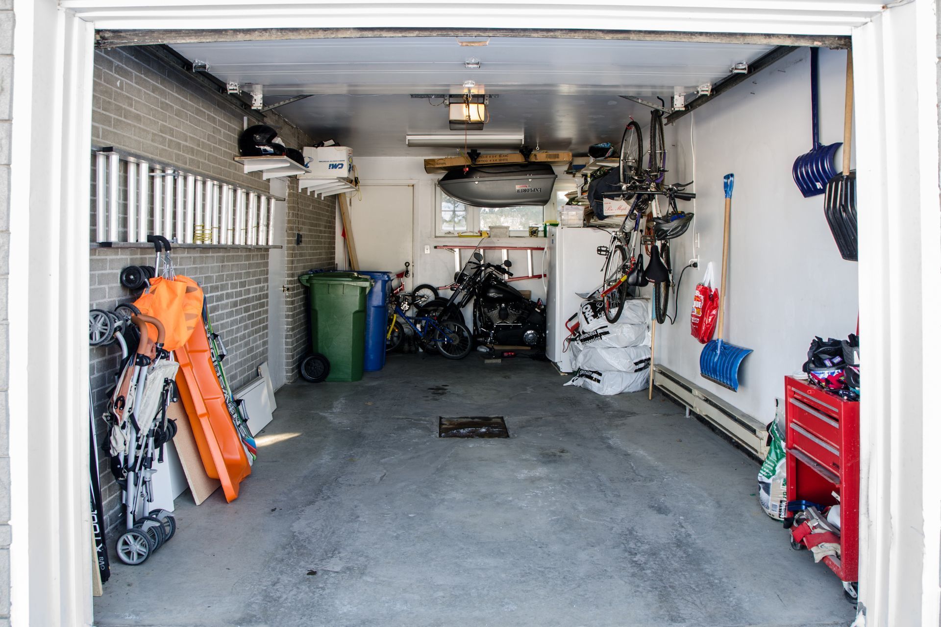 A garage filled with bikes , a snow blower , and other items.
