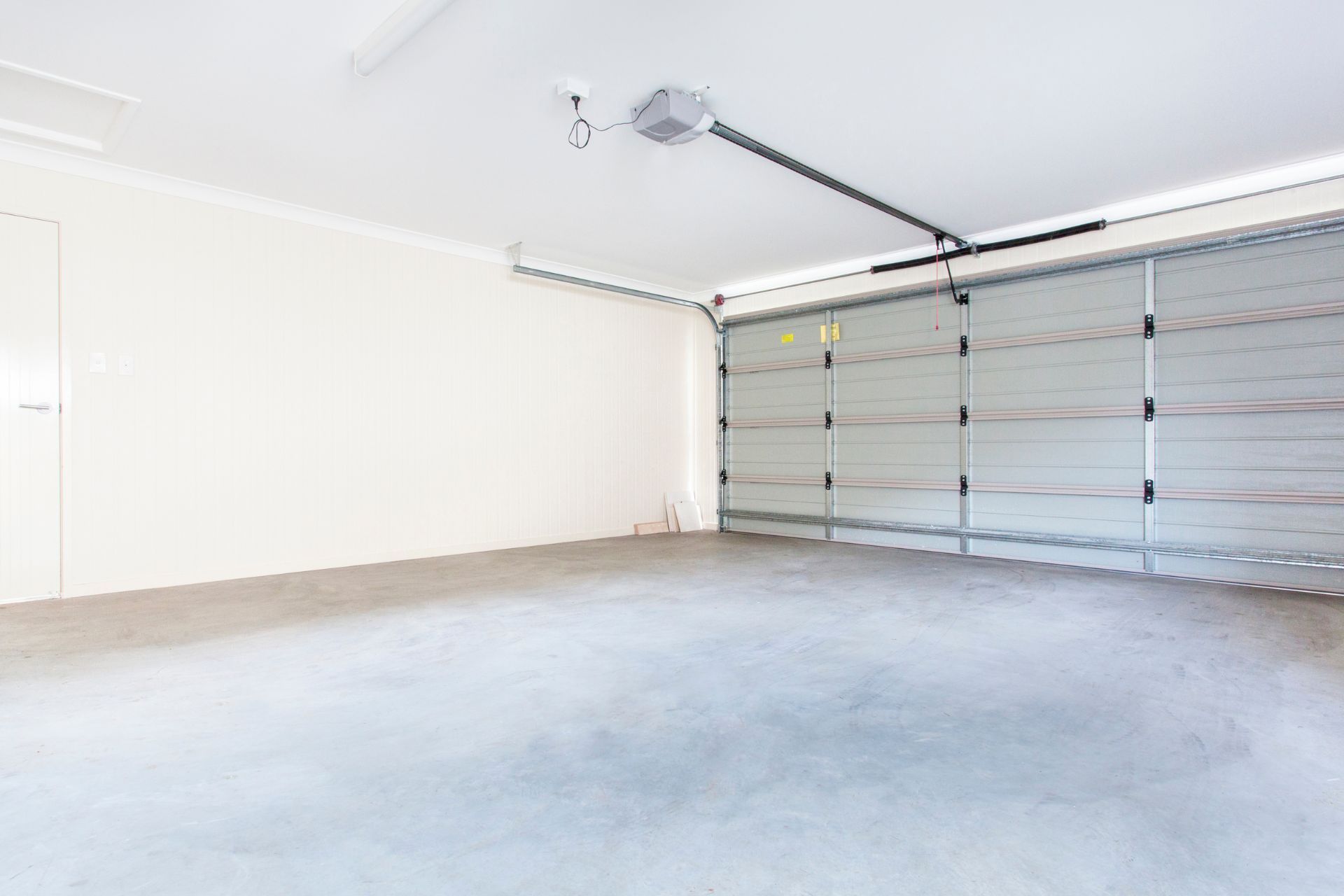 An empty garage with a garage door open and a ceiling fan.