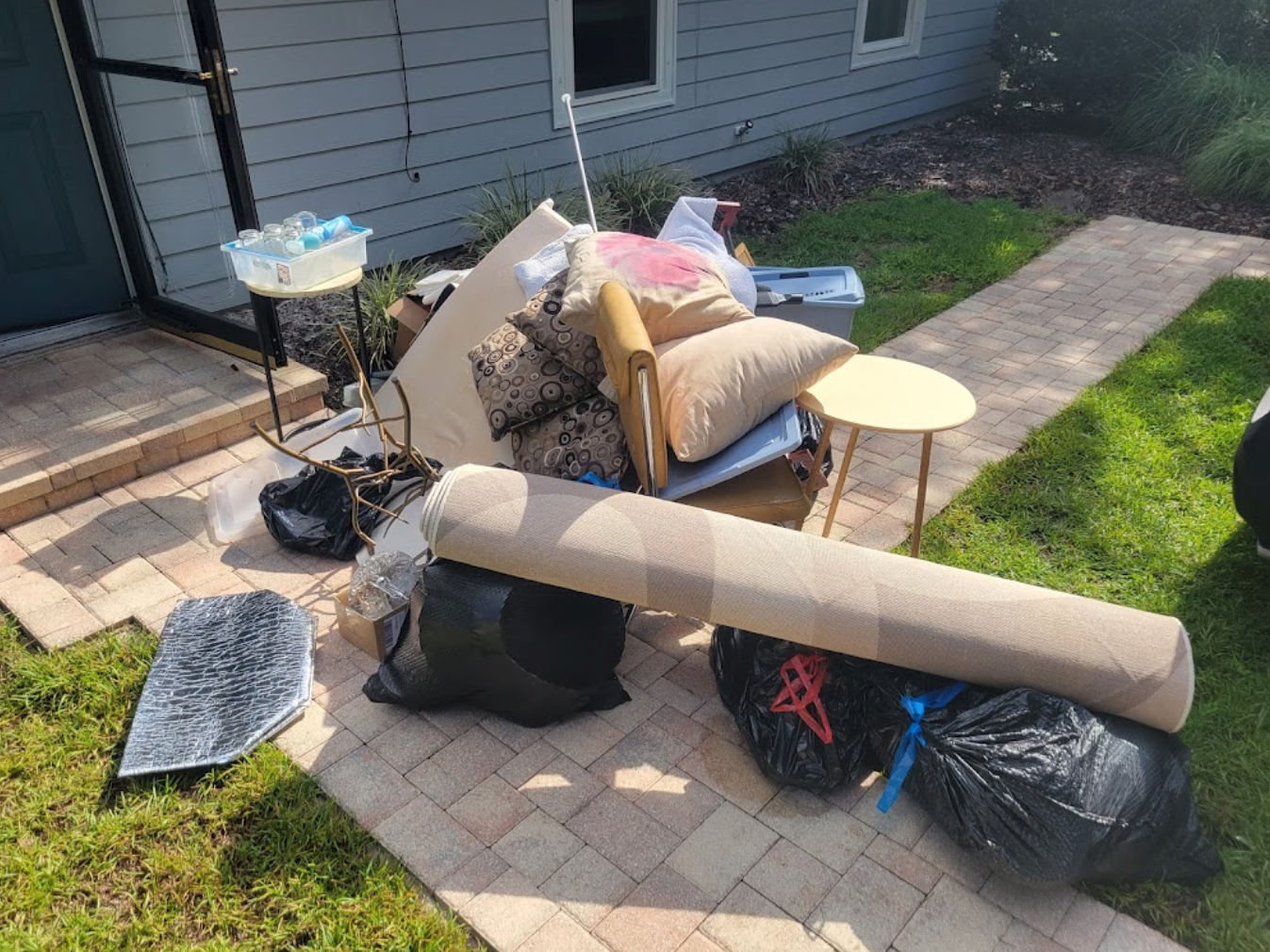 A pile of trash is sitting on the sidewalk in front of a house.