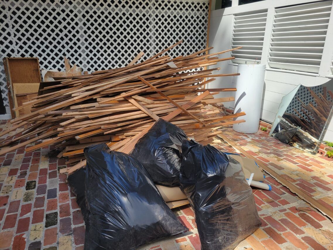 A pile of wood and trash bags on a brick floor