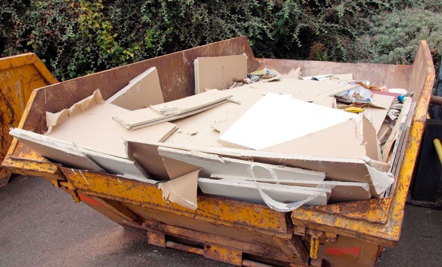 A dumpster filled with cardboard is sitting on the ground.