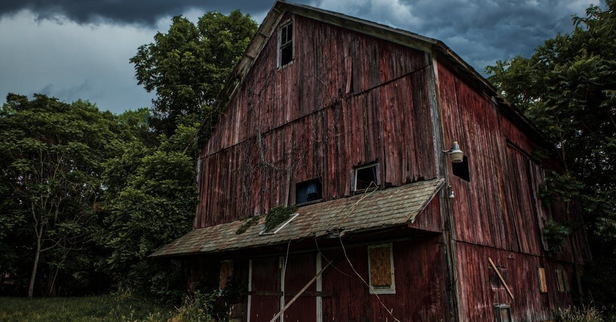 An old red barn is sitting in the middle of a field.