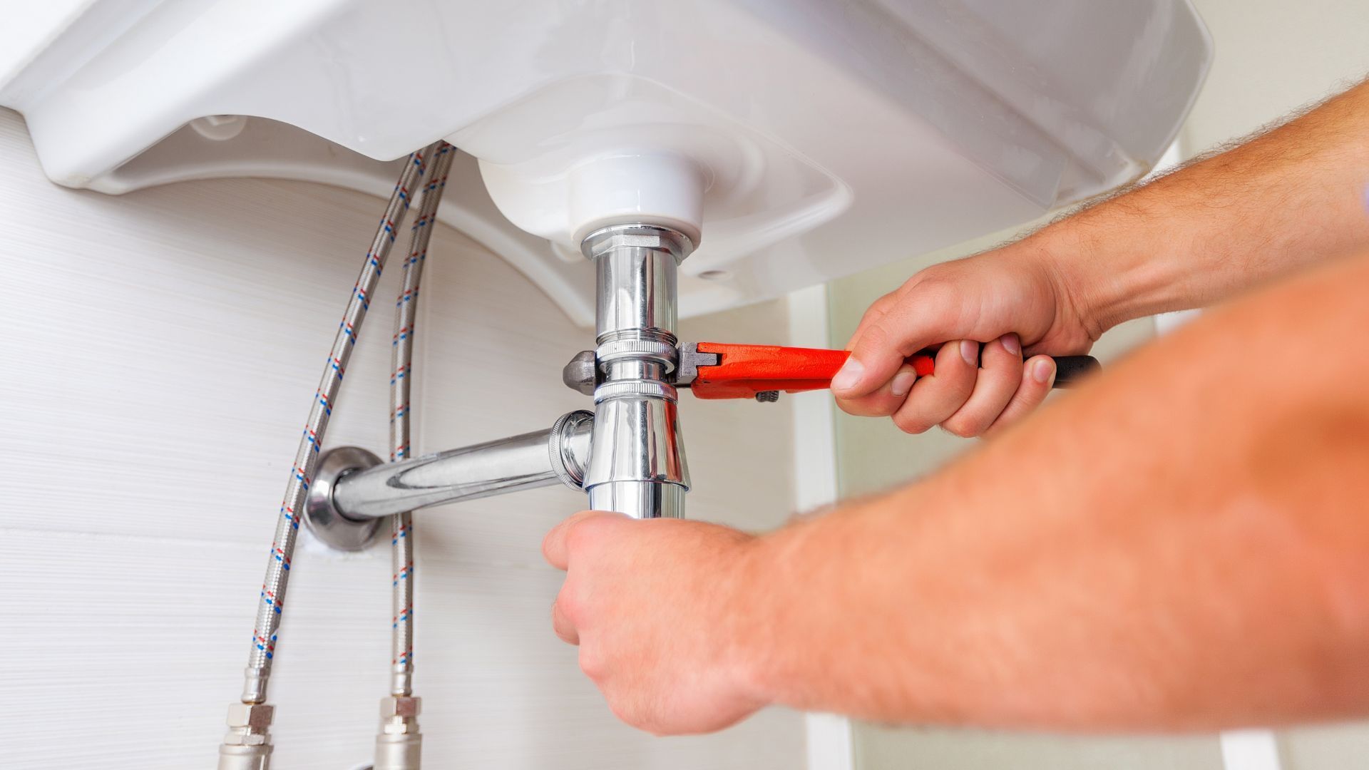 A man is fixing a water heater in a bathroom.