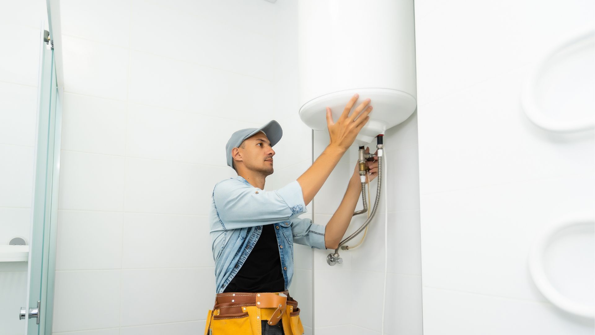A man is installing a water heater in a bathroom.