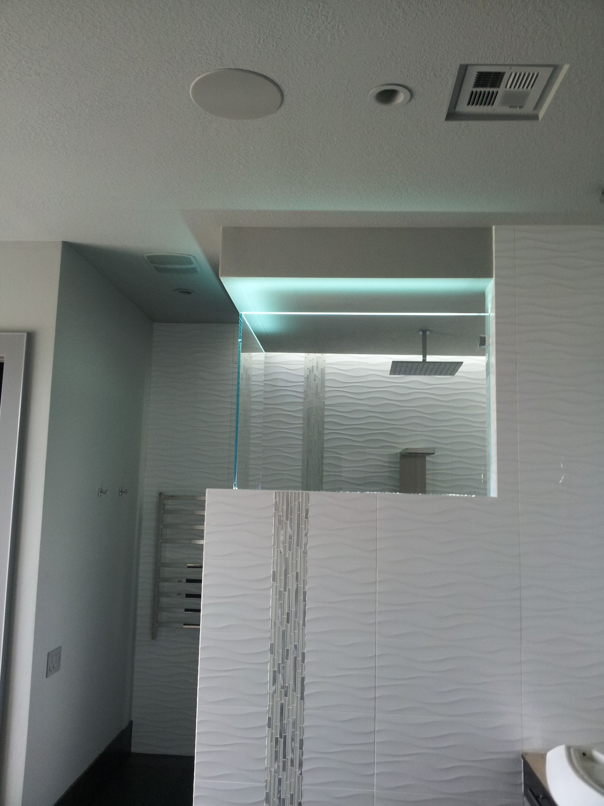 A bathroom with white tiles and a ceiling fan