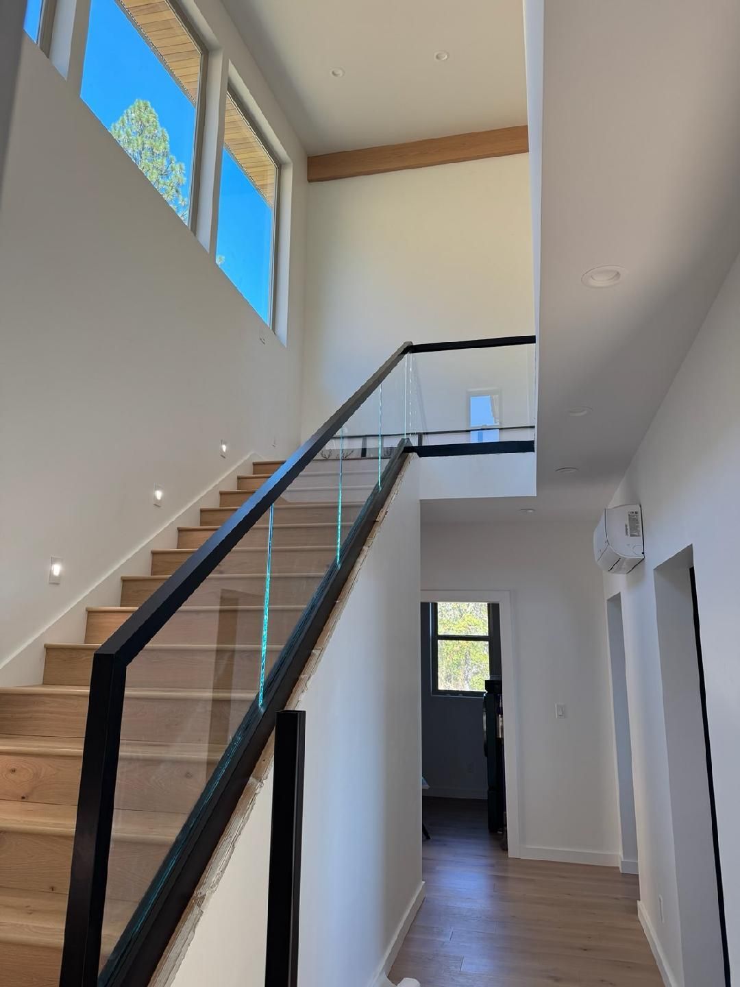 A hallway with stairs and a glass railing in a house