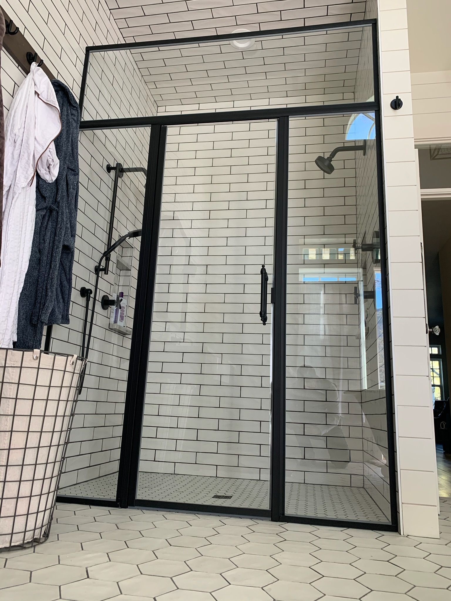A bathroom with a black shower door and white tiles