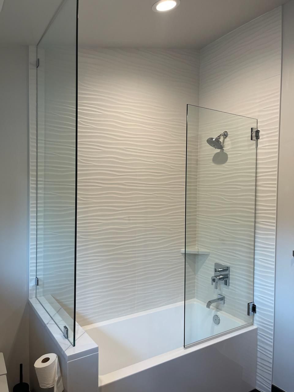 A bathroom with a bathtub and a glass shower door