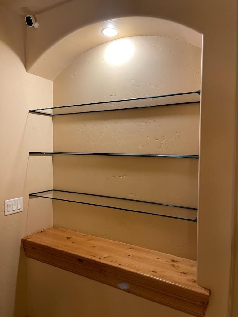 A corner of a room with shelves and a wooden counter top.