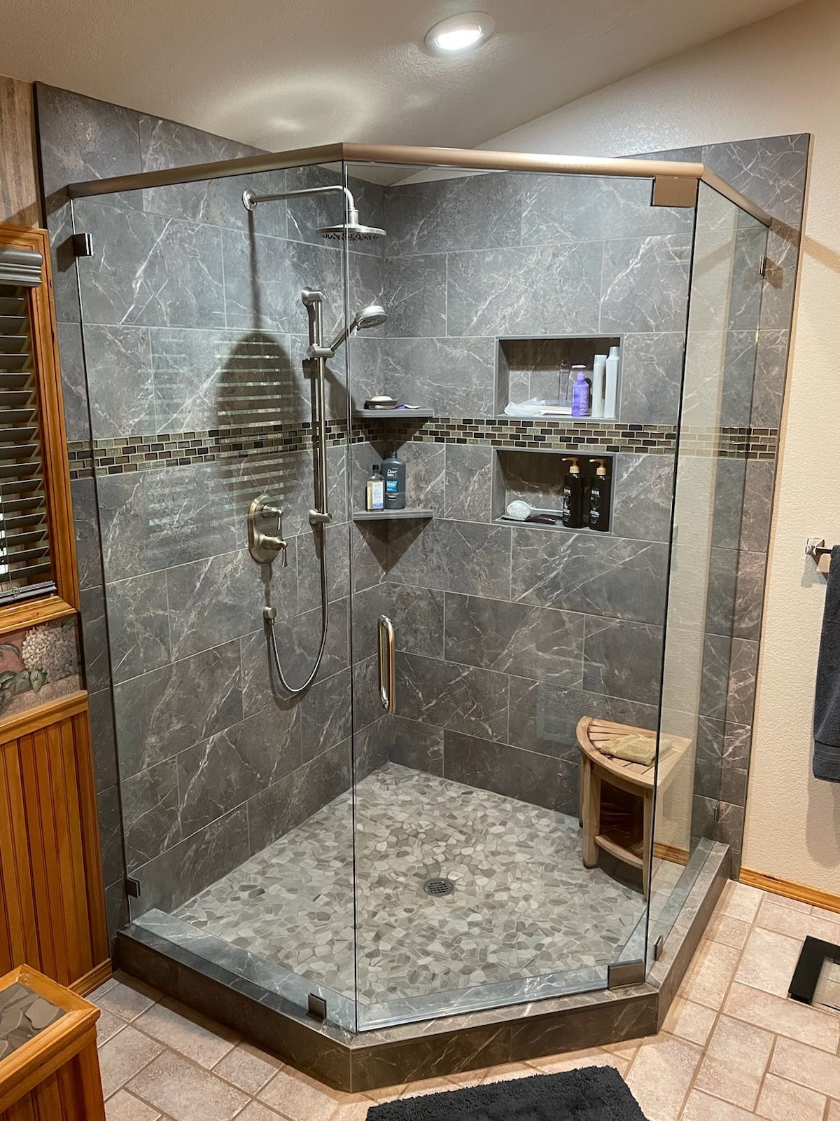 A bathroom with a walk in shower with a glass door.