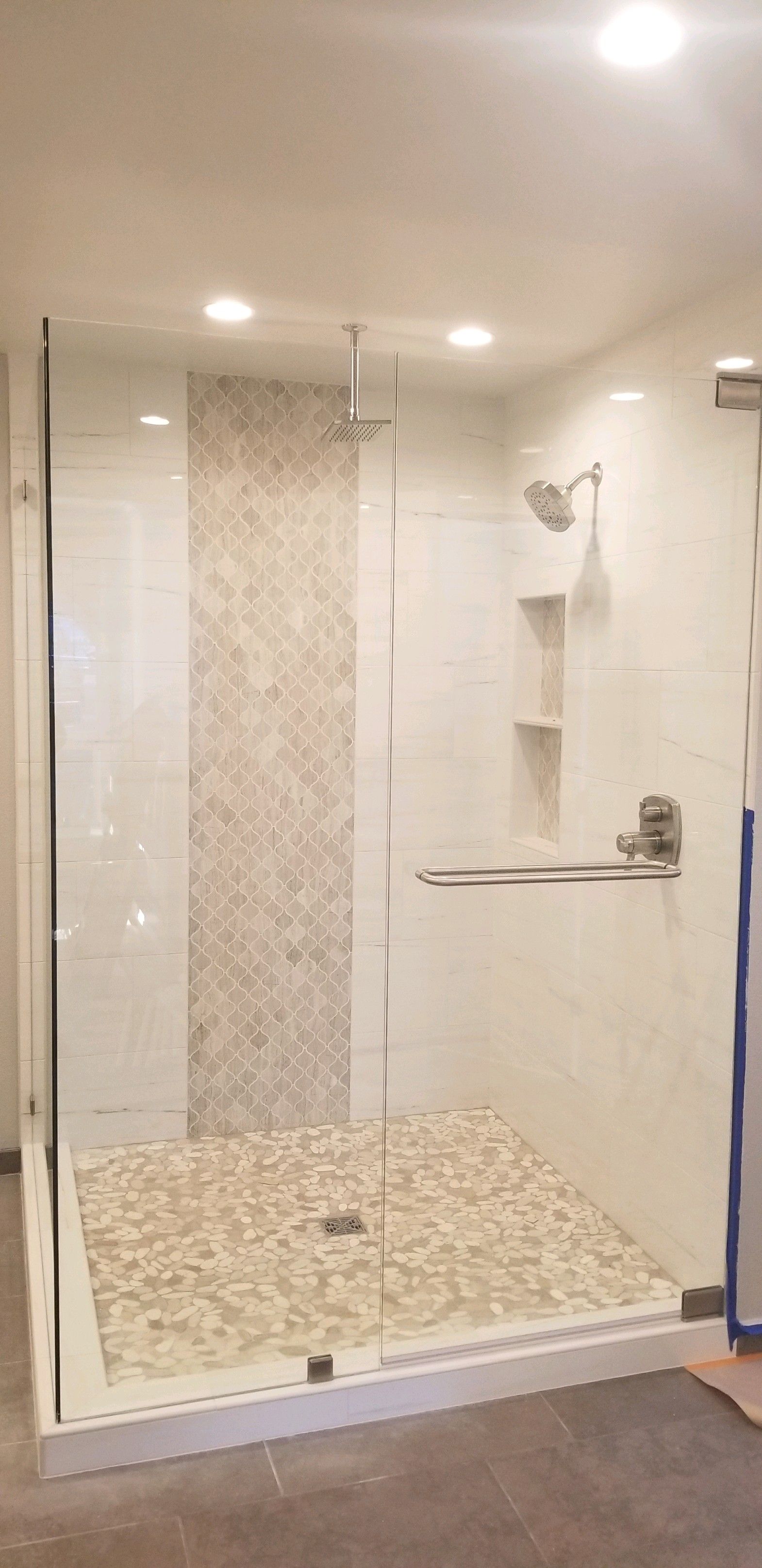 A bathroom with a walk in shower with a glass door.