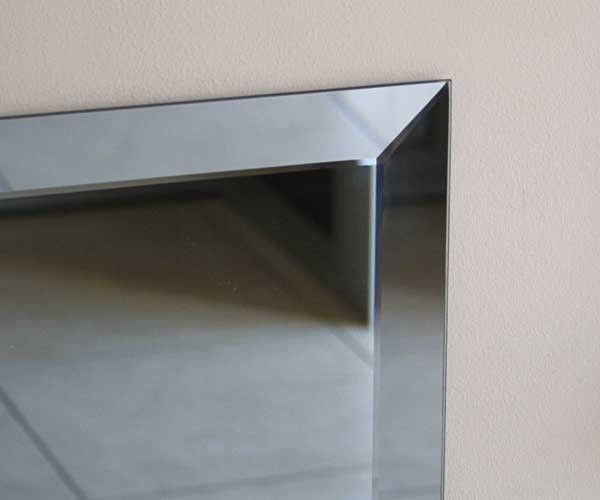 A close up of a mirror with a metal frame on a wall.