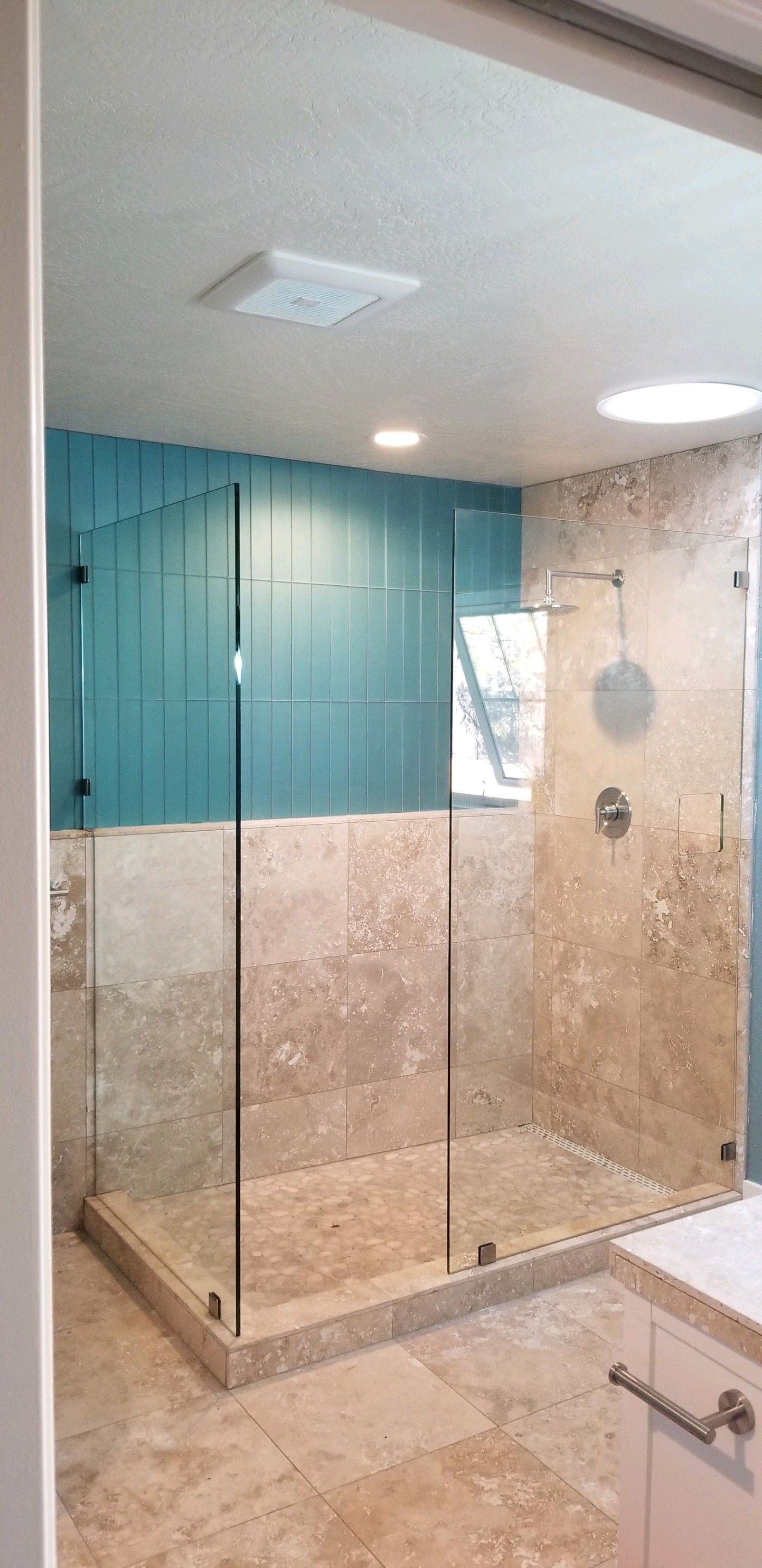 A bathroom with a walk in shower and a sink.