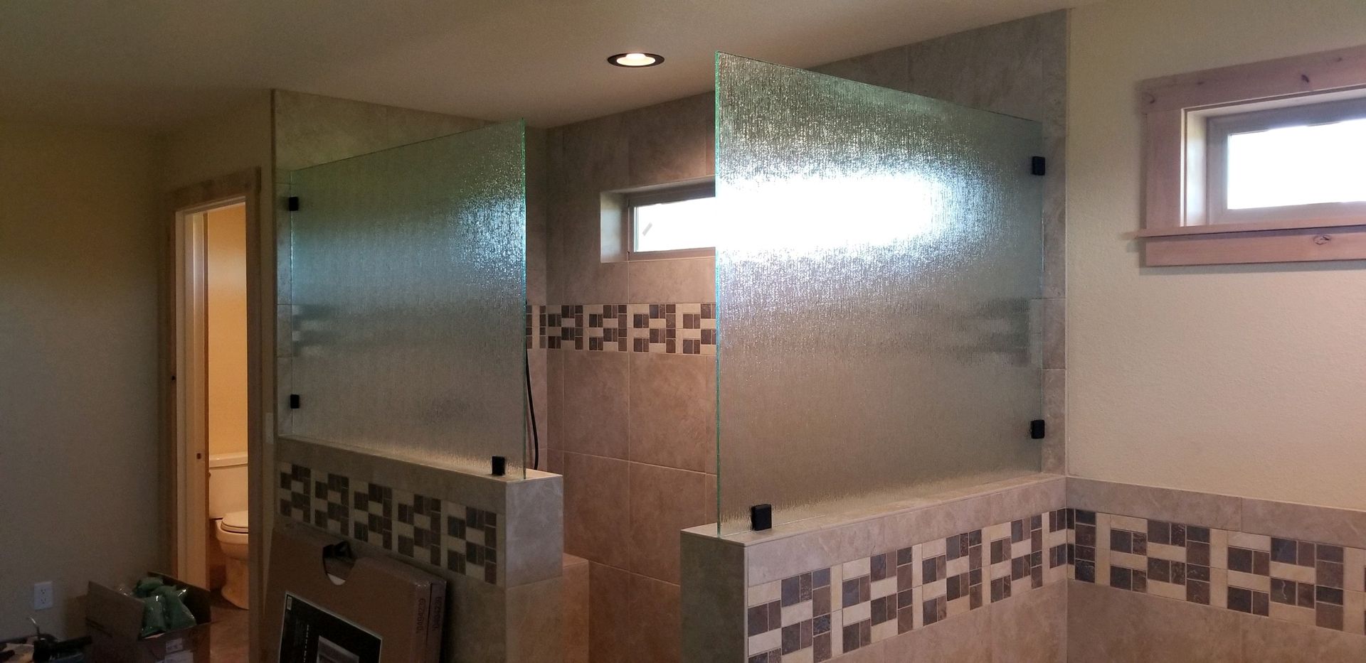 A bathroom with a glass shower door and a window.