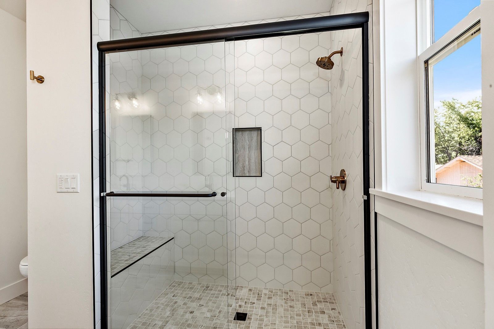 A bathroom with a sliding glass shower door and a window.