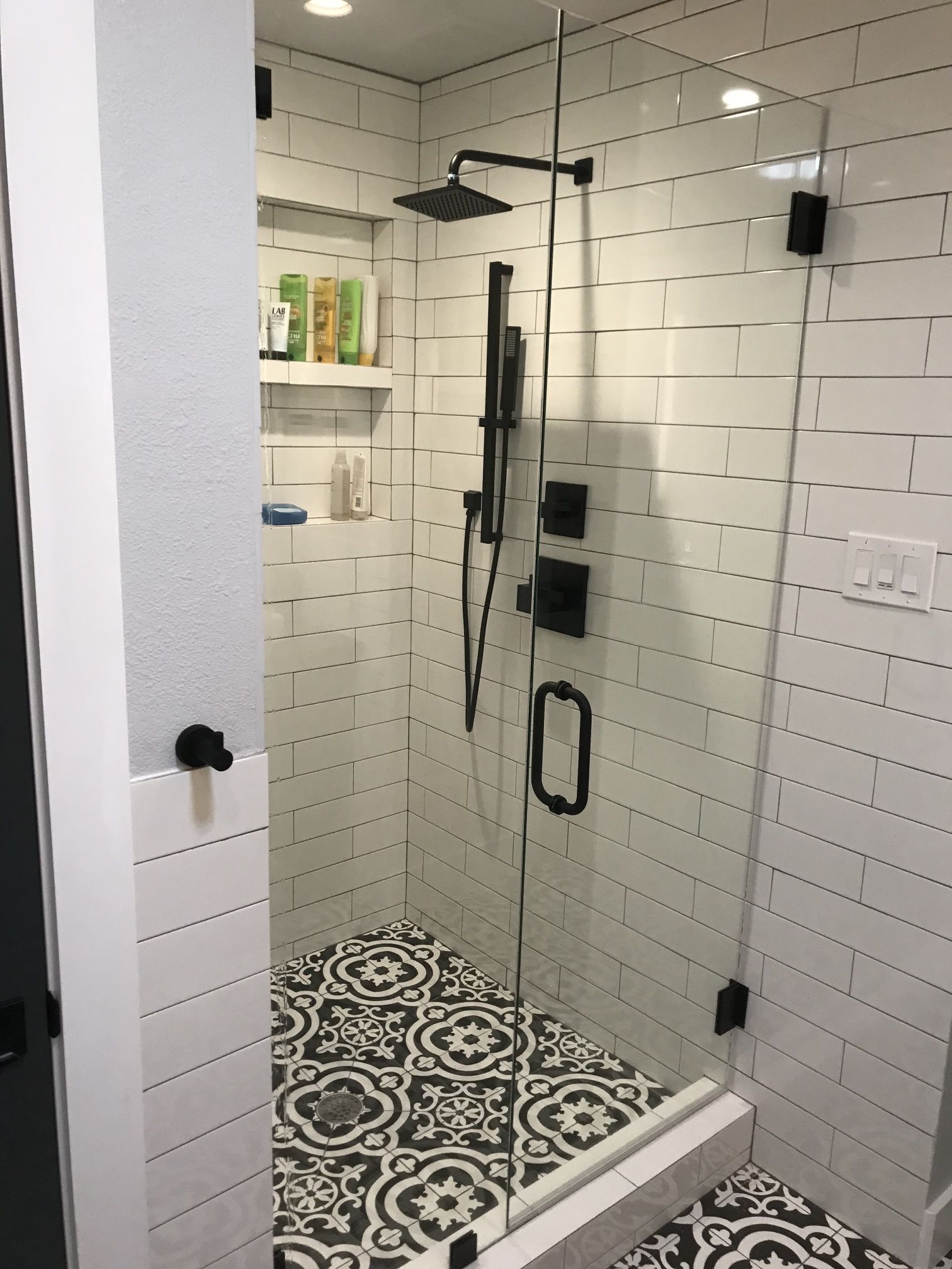 A bathroom with white tiles and a walk in shower