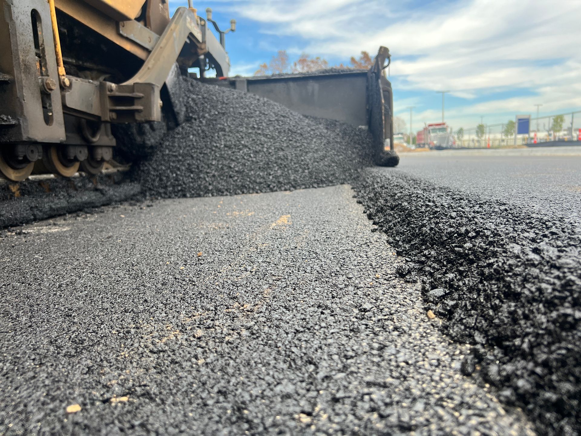Asphalt paving machine laying down a fresh layer of black asphalt on a road.