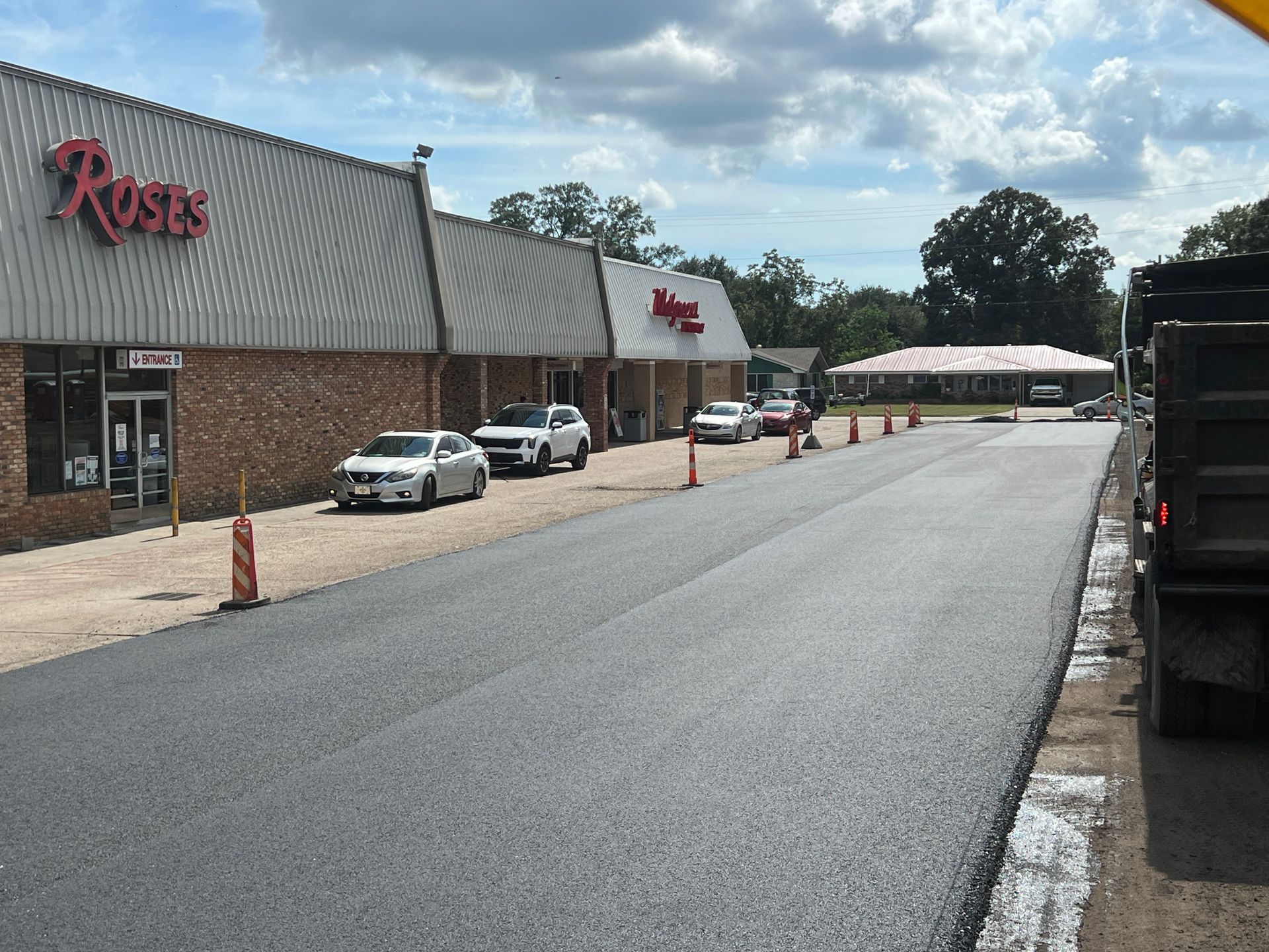 A truck is parked on the side of the road in front of a store.