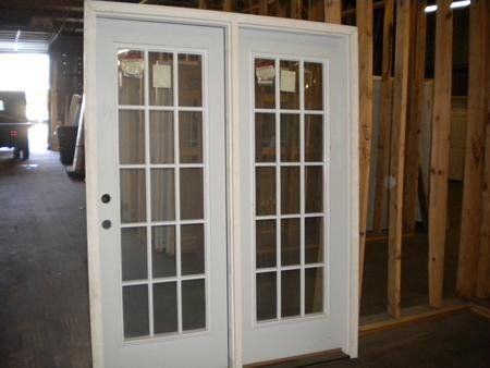 A pair of white french doors are sitting in a building under construction.