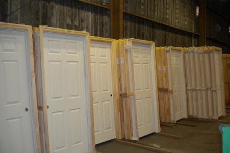 A warehouse filled with lots of white doors in wooden boxes.