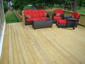 A wooden deck with a couch and chairs on it