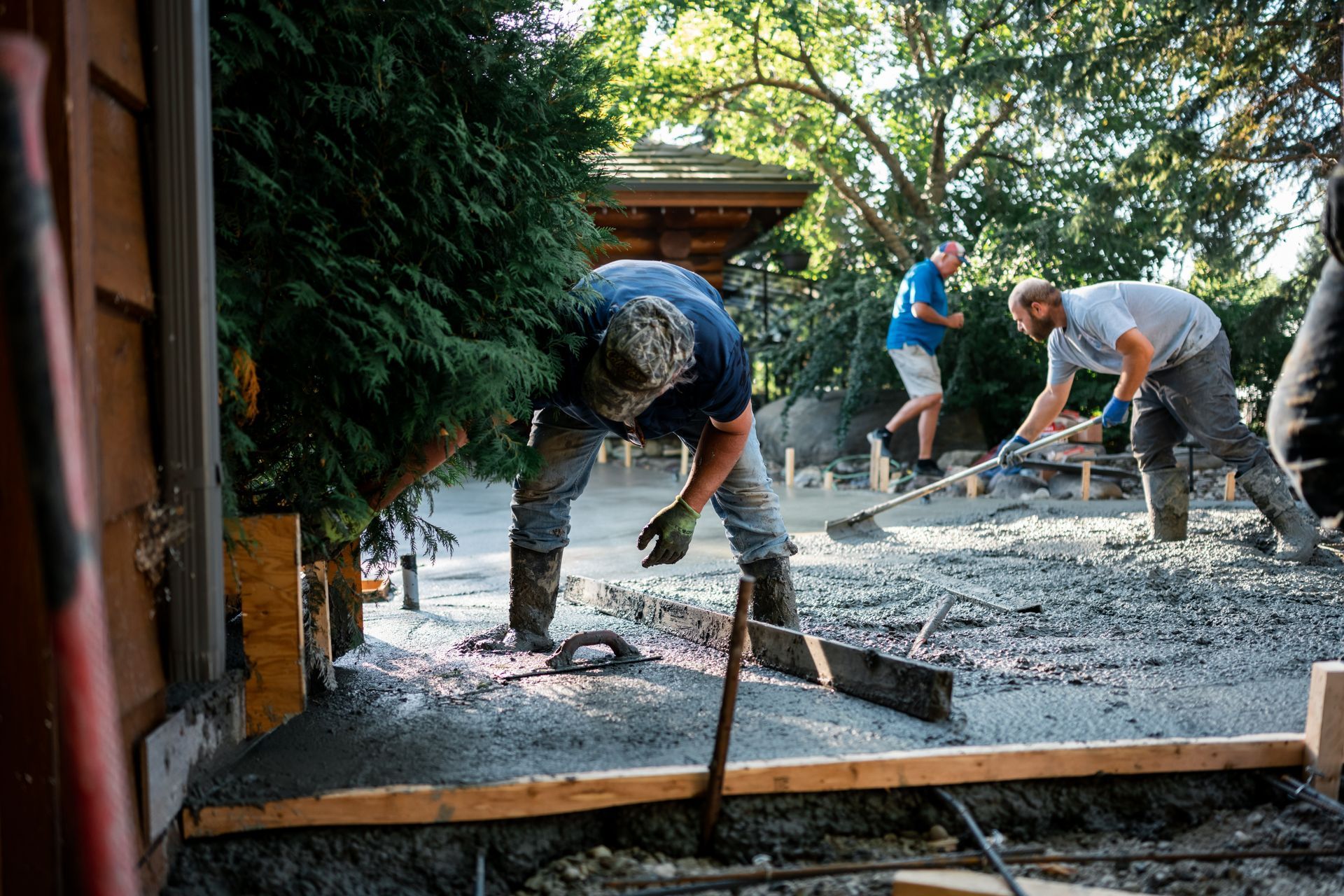 A group of men are working on a concrete driveway.