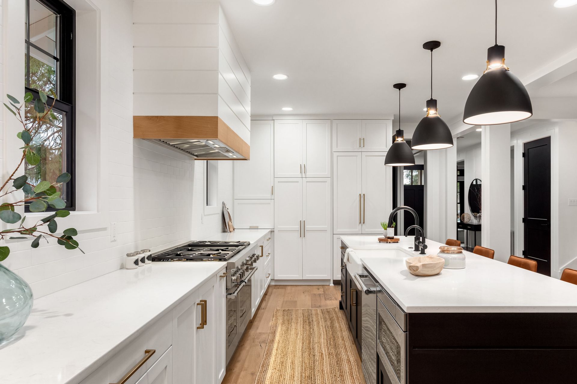 Modern white kitchen with island, wood accents, and pendant lights.