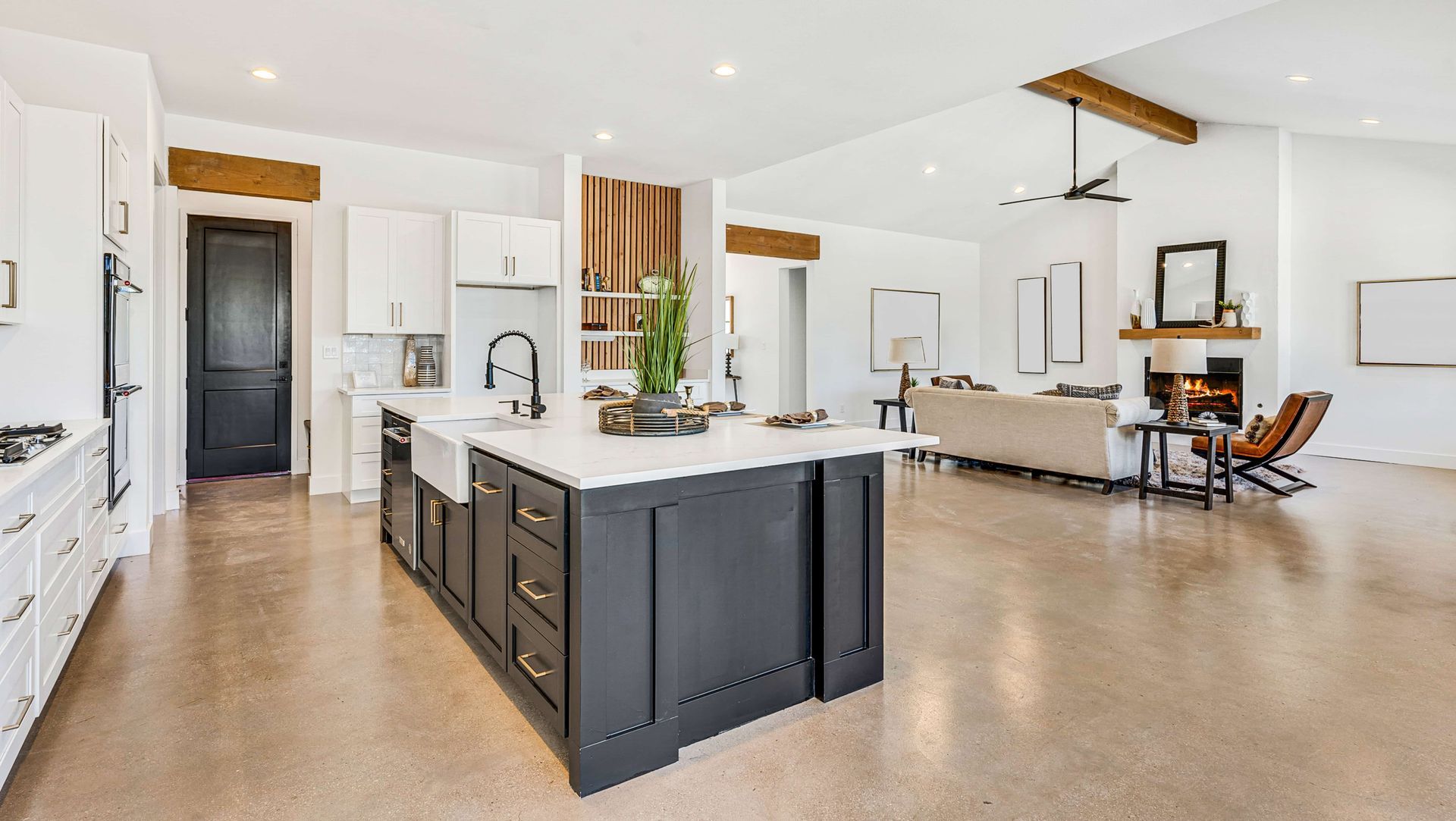 Modern kitchen with dark island, white cabinets, and living room with fireplace.