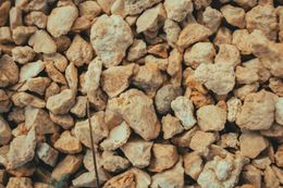 Close-up of a pile of light-colored, beige and brown gravel stones.