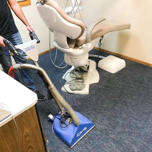 A man is using a vacuum cleaner to clean a dental chair