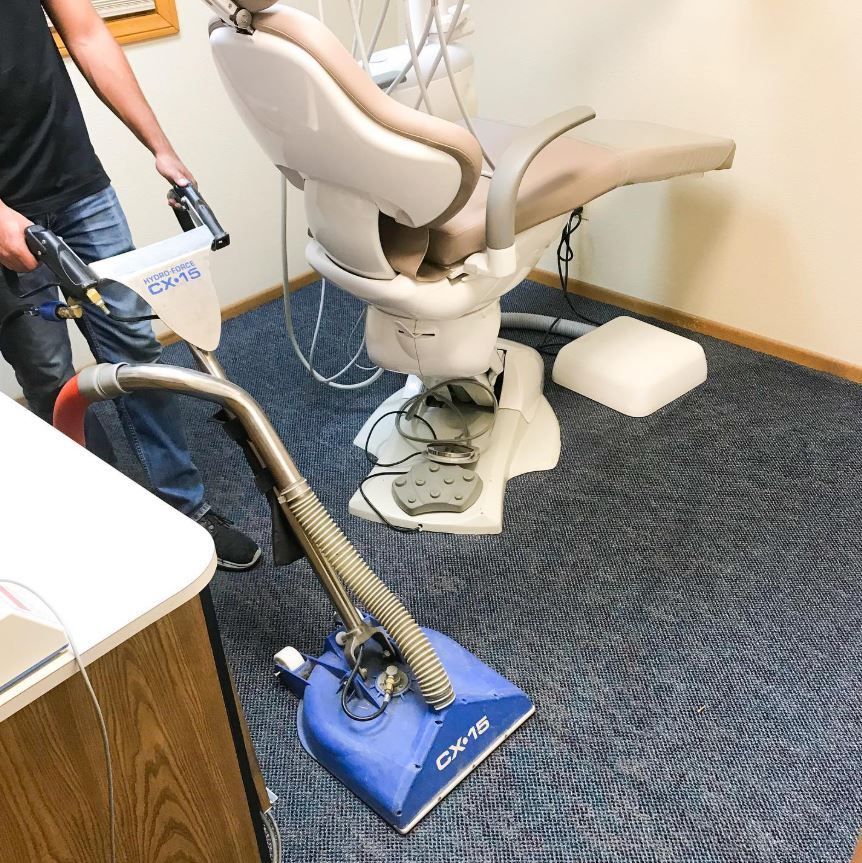 A man is using a vacuum cleaner to clean a dental chair
