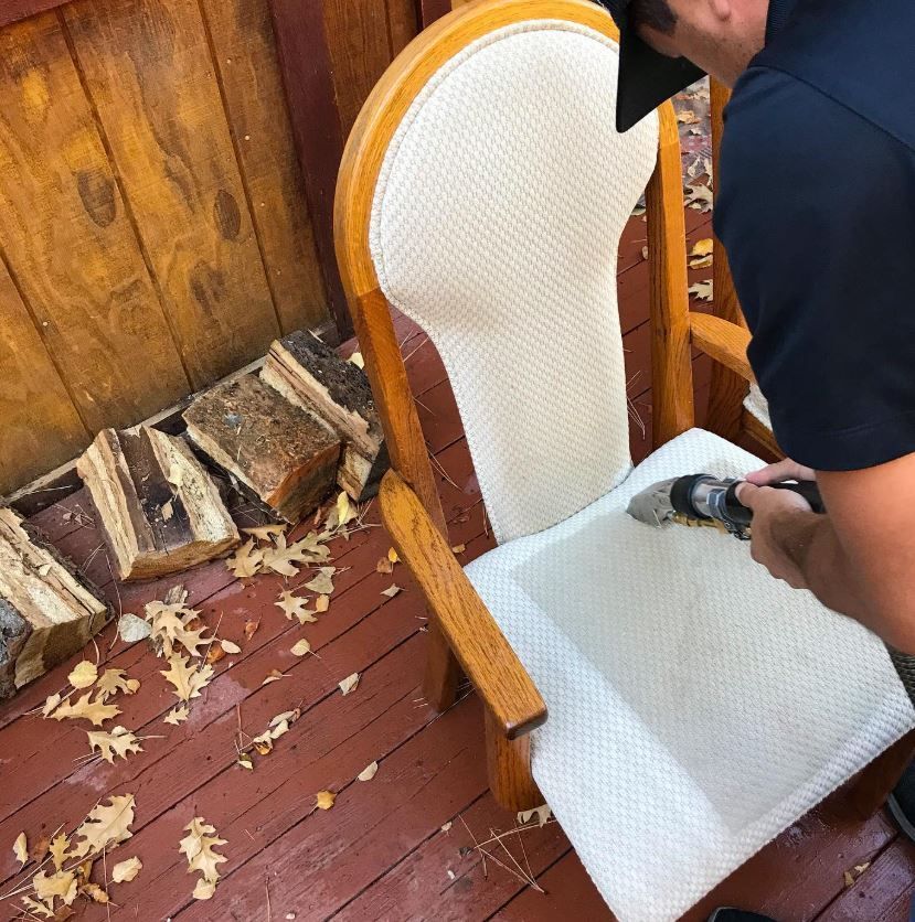 A man is cleaning a chair with a brush