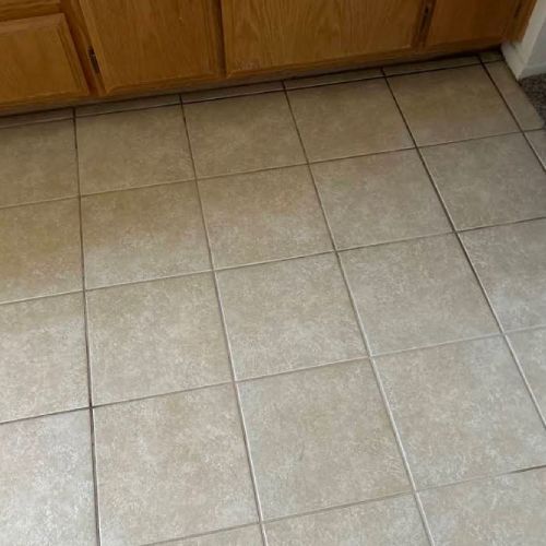A close up of a tiled floor in a kitchen with wooden cabinets.