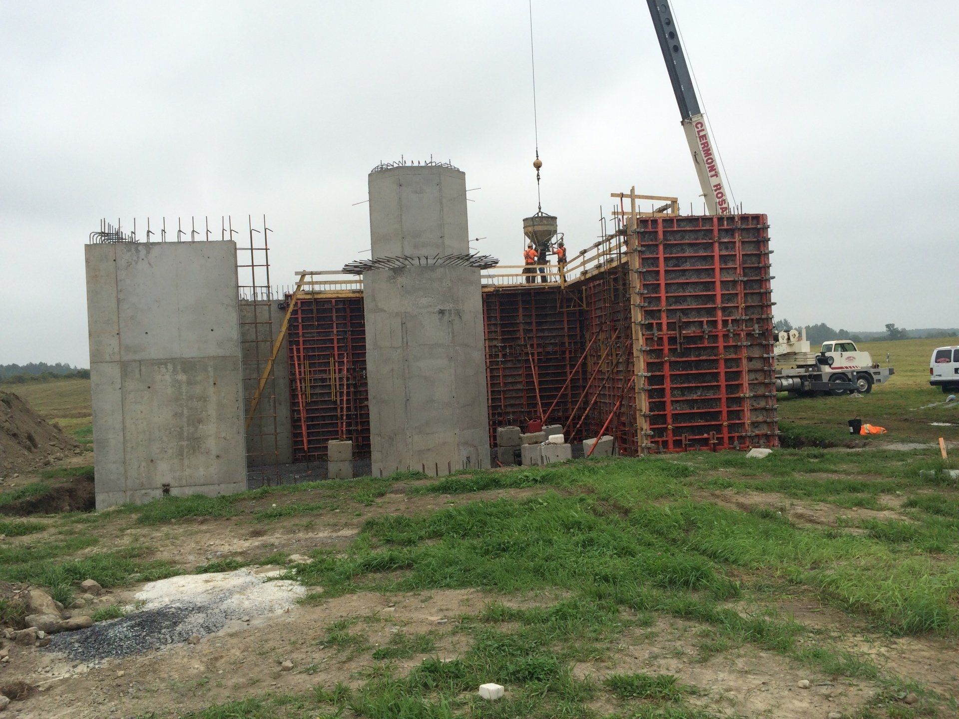 A large concrete structure is being built in a field with a crane.
